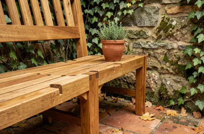 Banc de jardin en teck artisanal avec détail de mortaise et tenon sur terrasse en pierre